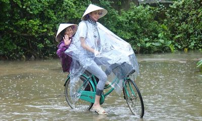 Hoa hậu Phạm Hương chạy xe đạp chở cụ già trong cơn mưa dầm