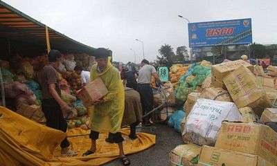 Container chở hoa quả lật nghiêng, dân đội mưa khiêng hàng giúp tài xế