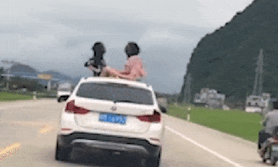 Lạnh người cảnh mẹ lái xe phăng phăng trên đường mặc 2 con gái cười đùa trên nóc ô tô