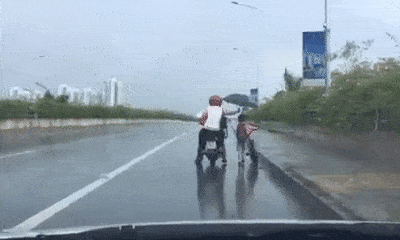 Đôi vợ chồng đội mưa che ô cho bé trai dắt xe đạp, dân tình hết lời khen ngợi
